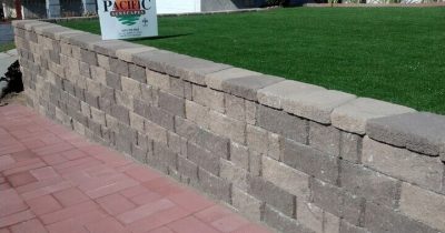 A retaining wall made of concrete blocks to protect the luscious green lawn